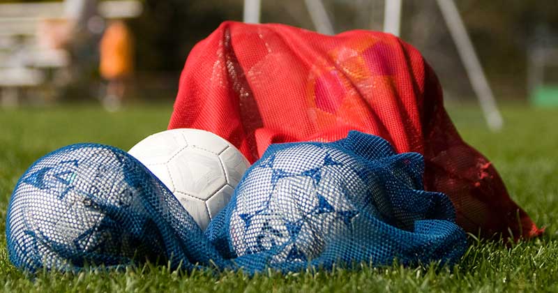 footballs in a bag on a pitch
