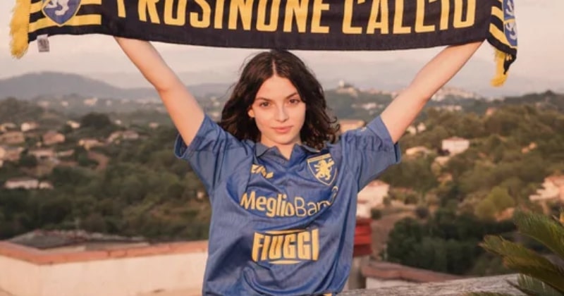 model wearing frosinone 2023-24 third shirt in blue holding team scarf