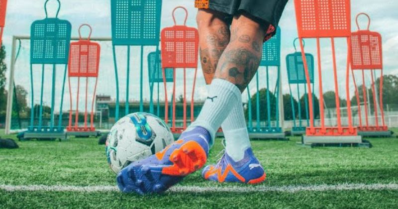 puma future football boots in blue and orange on feet kicking football