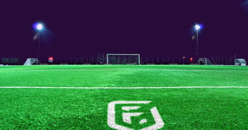 empty 3G artificial grass football pitch at night with floodlights