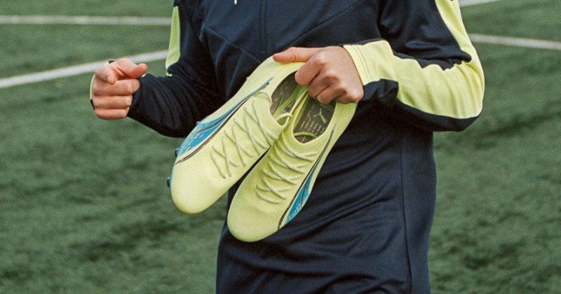 player holding puma ultra football boots on training ground