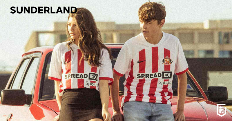 two models sat on a car wearing sunderland 2023-24 home shirts in red and white
